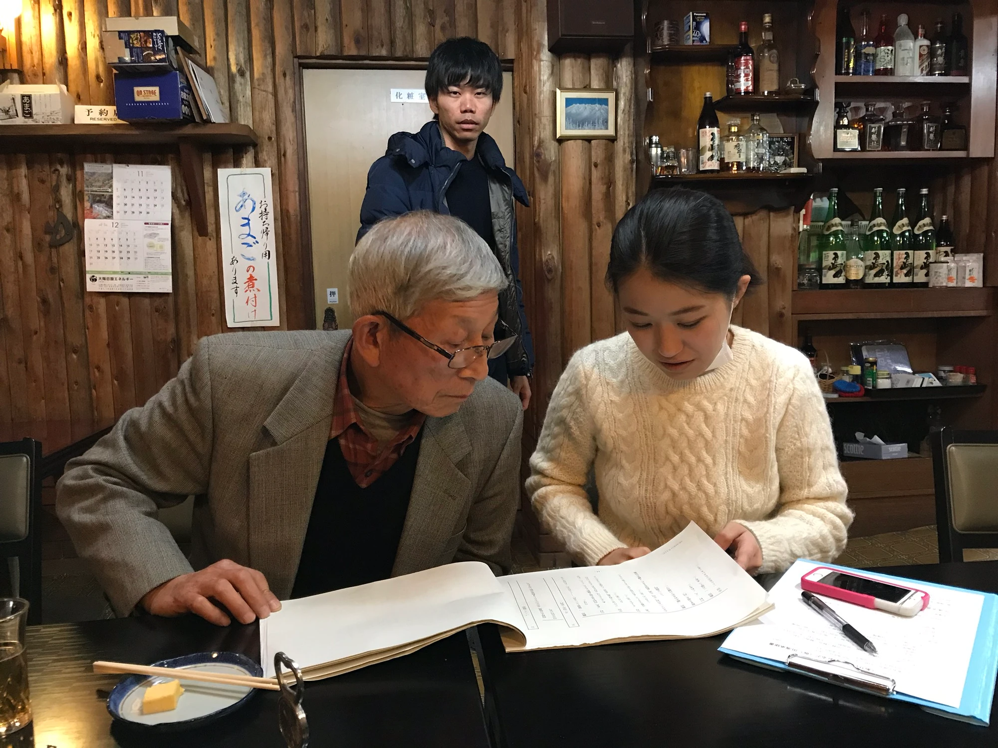 店内のテーブルで台本を開いて確認する映画の出演者たち